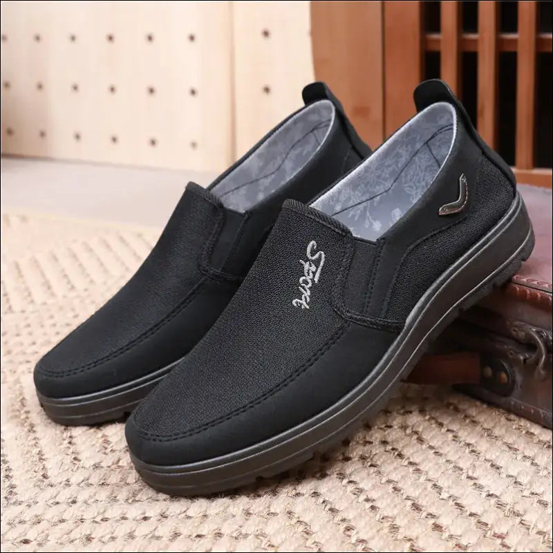 Pair of black slip-on canvas shoes with gray interior lining.