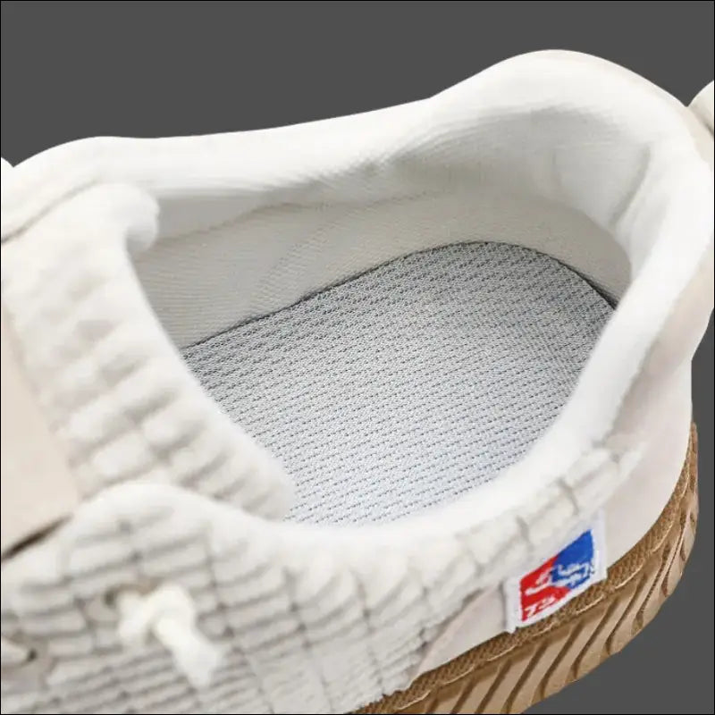 White sneaker with a textured upper and visible inner lining.