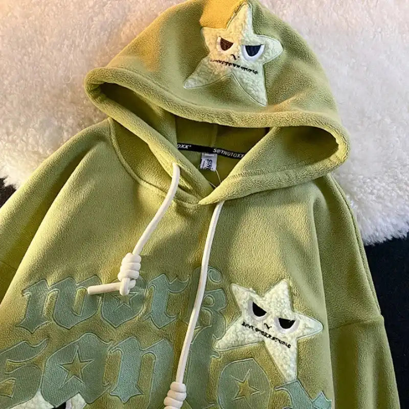 Light green hoodie with star-shaped character designs on the hood and chest.