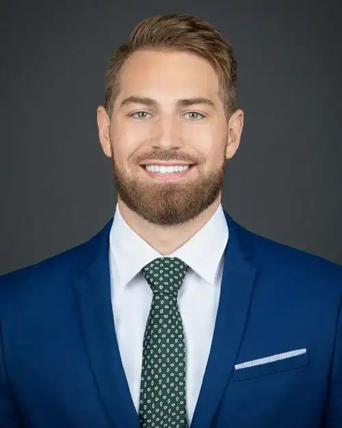 Smiling man in a blue suit and green patterned tie.