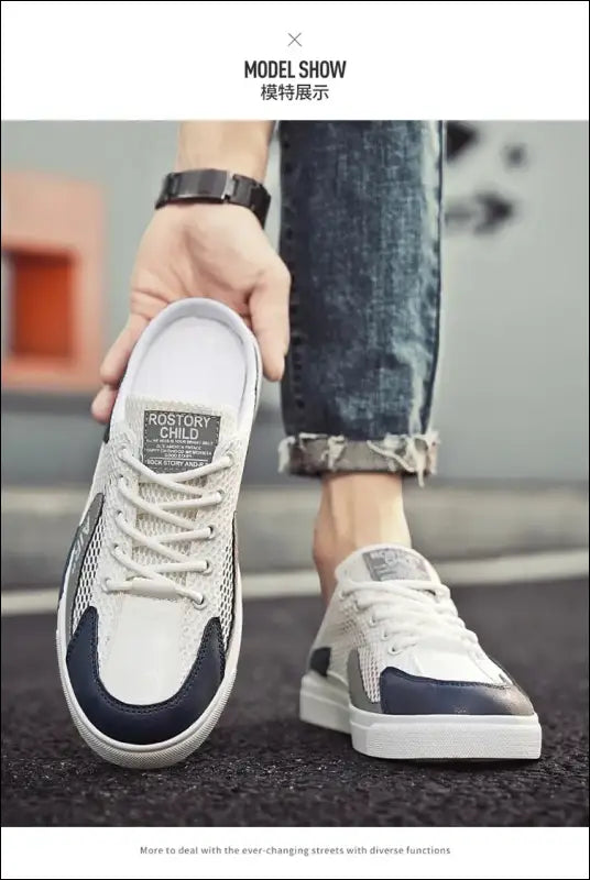 Pair of white and navy blue sneakers worn on feet with cuffed jeans.