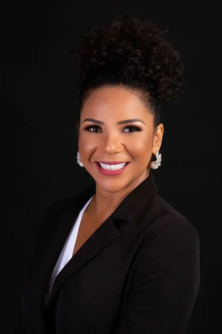 Smiling woman with curly updo hairstyle wearing a black blazer and white top.