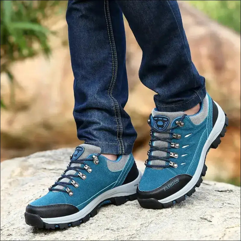 Blue and gray hiking shoe with rugged soles on a rocky surface.