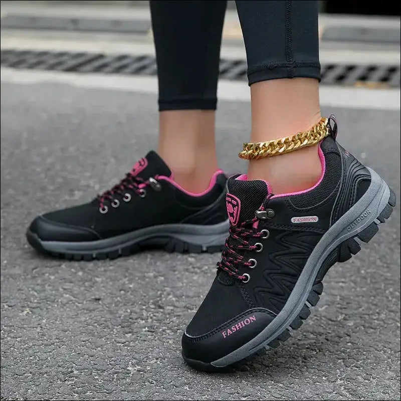 Black athletic shoe with pink accents and laces.